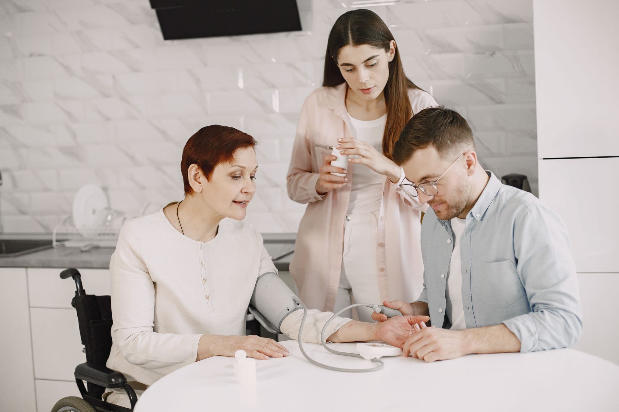 A CareBridge RN checking a patient's blood pressure at her kitchen table